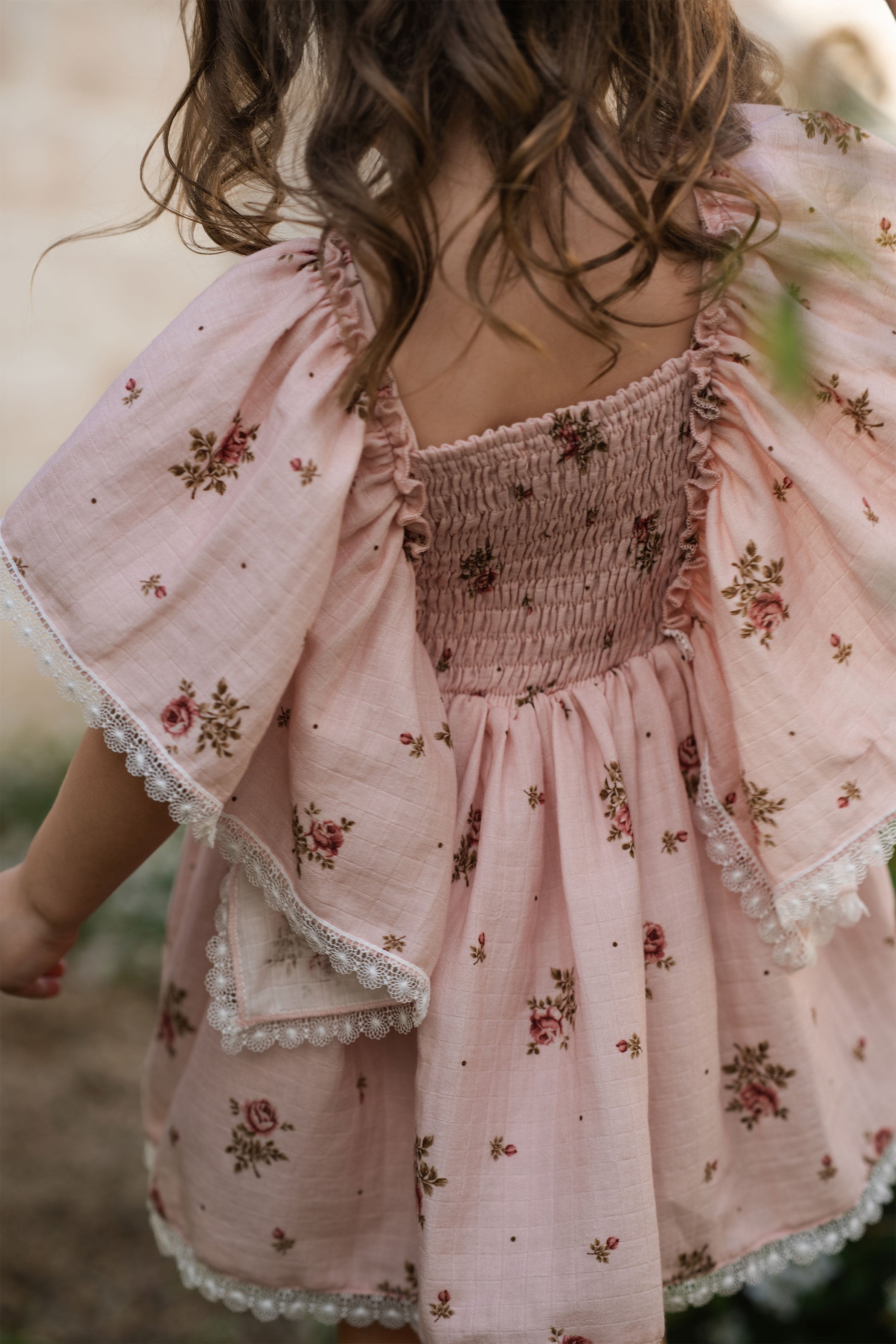 Child wearing a pink floral dress with a soft focus background