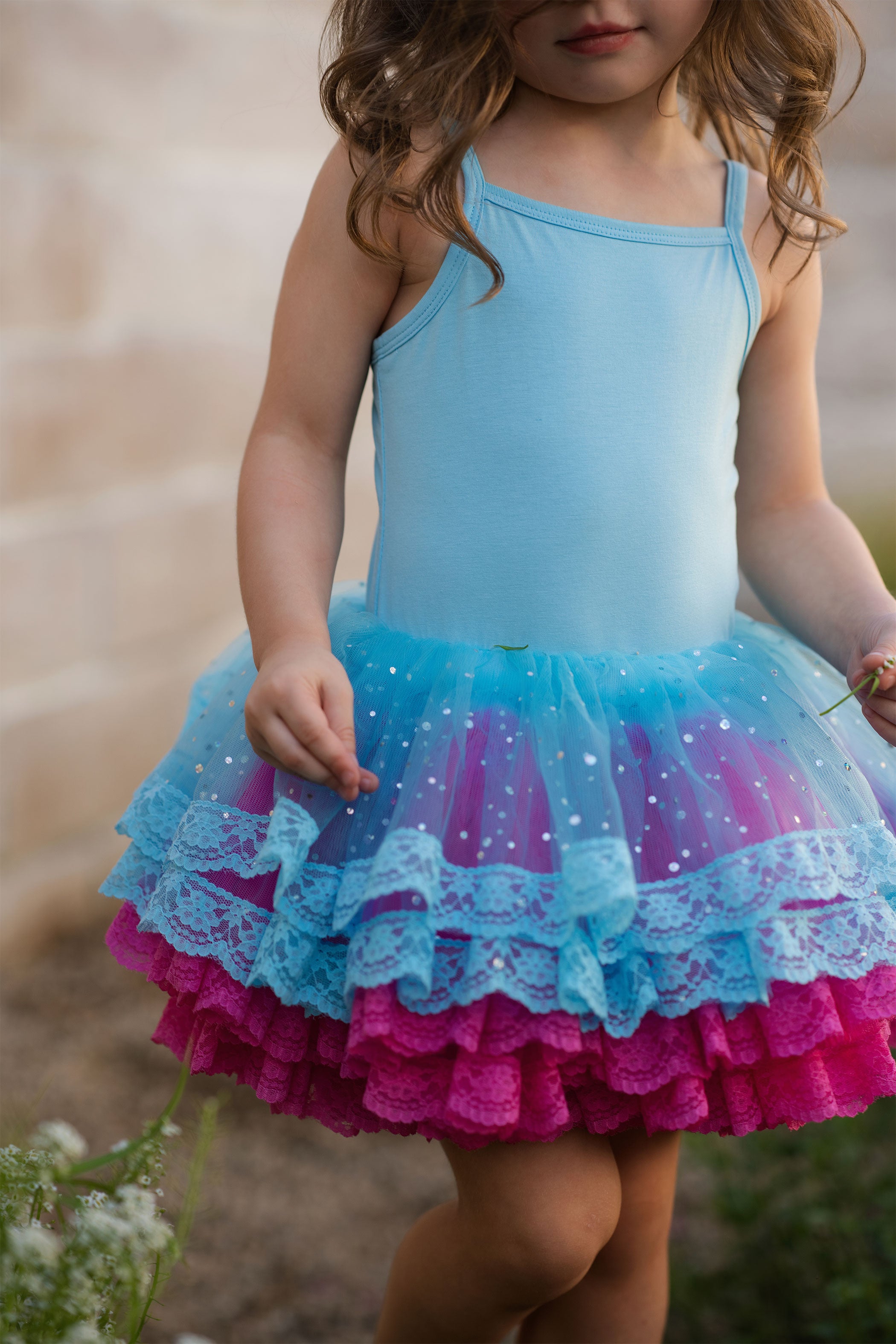 Child wearing a blue and pink dress with a tutu skirt outdoors.